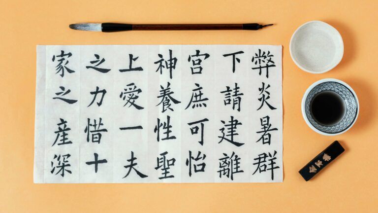A piece of paper with Chinese calligraphy, a brush, ink, and inkstone.