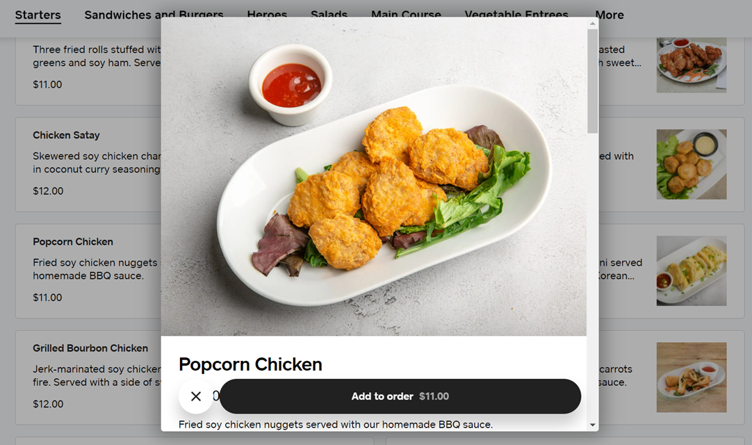 A plate of crispy popcorn chicken served with a side of sauce.