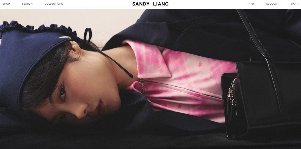 Fashion model with pink shirt and black handbag. Sandy Liang brand.