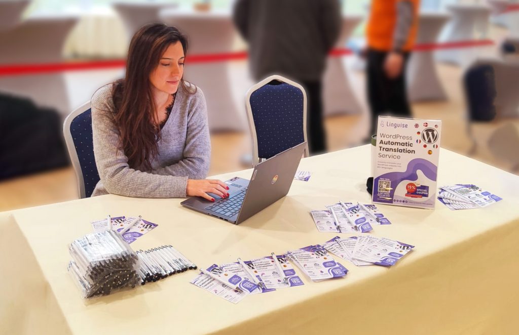 A woman using a laptop on a table with various flyers. She appears to be working or gathering information.